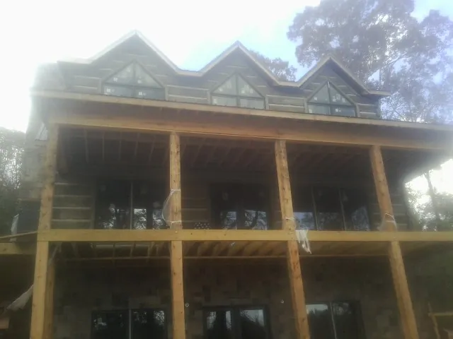 Dormers and porch framing on a large log home under construction — Roof Coating work by our crew in Bristol