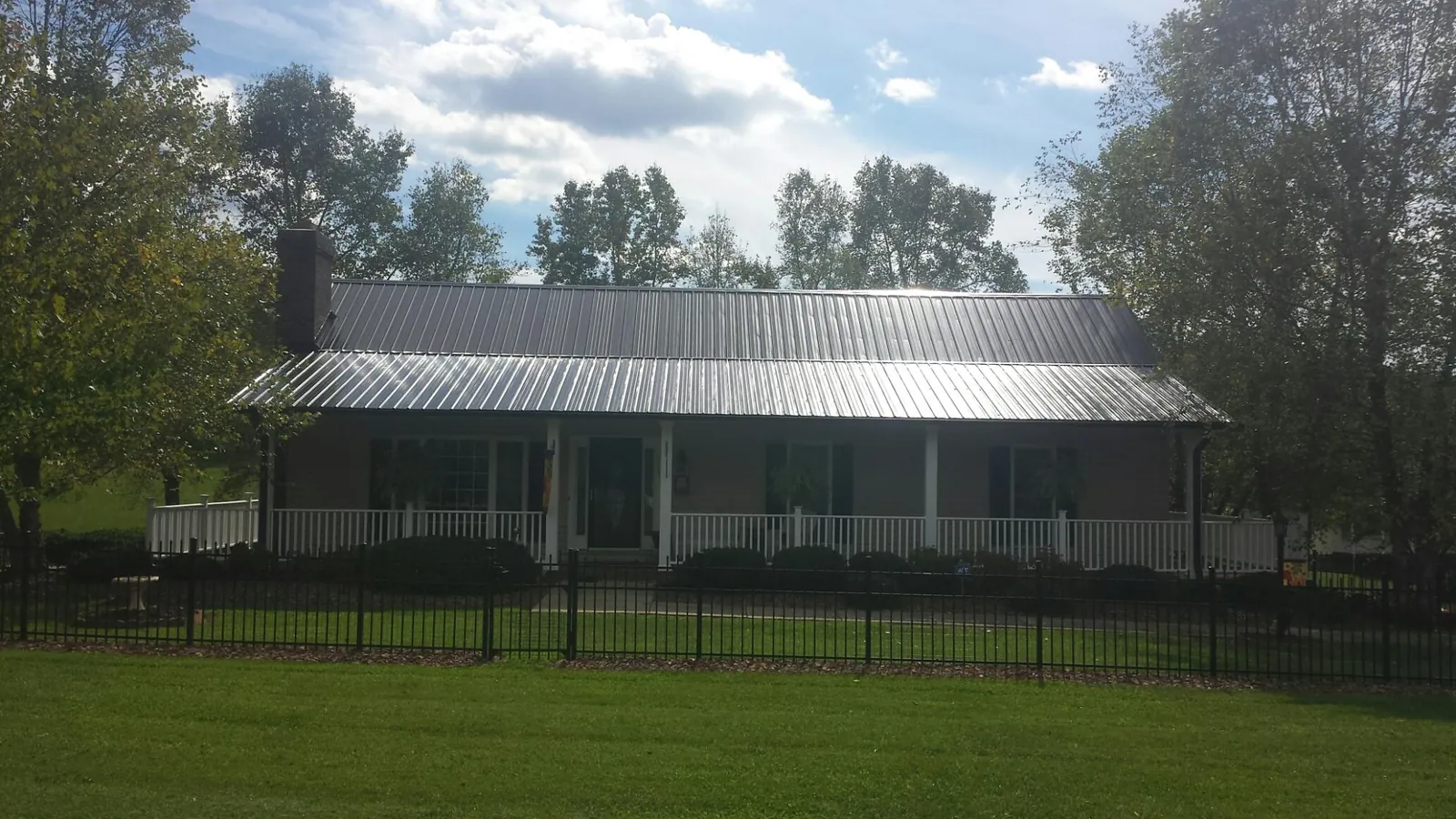 Gray metal roof on a brick ranch with a full width front porch — Gutter Guard Installation work by our crew in Bristol